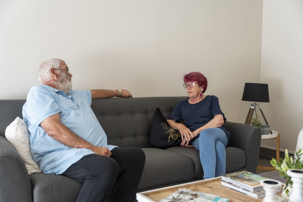 Man and woman chatting on a couch inside a retirement village unit