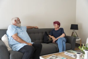 Man and woman chatting on a couch inside a retirement village unit